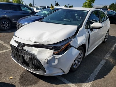 Damage to the front and side of a white Toyota sedan parked in a lot, highlighting the impact from an accident. Relevant for auto insurance or safety discussions.